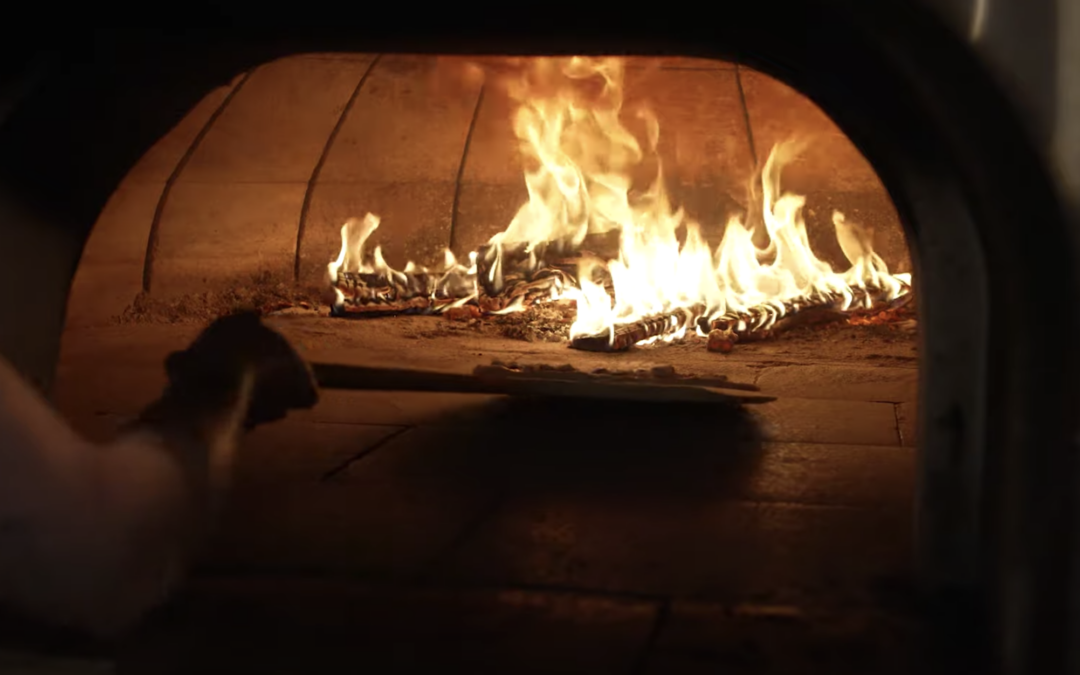 Pizza being placed into a wood fire oven