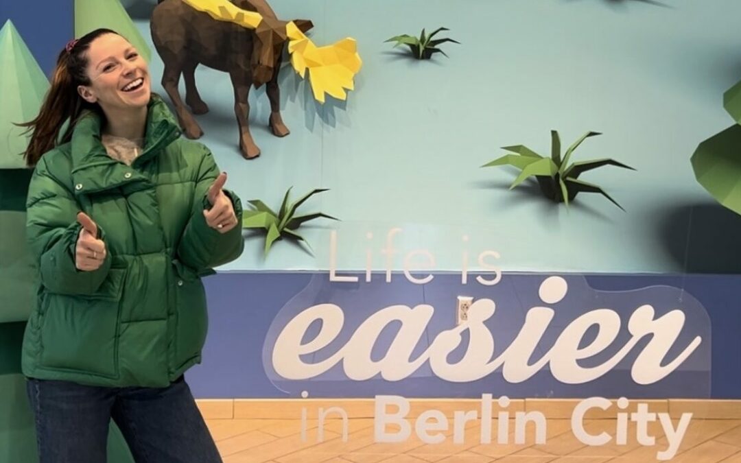 Sydney Hancock next to a sign that says "Life Is Easier in Berlin City"